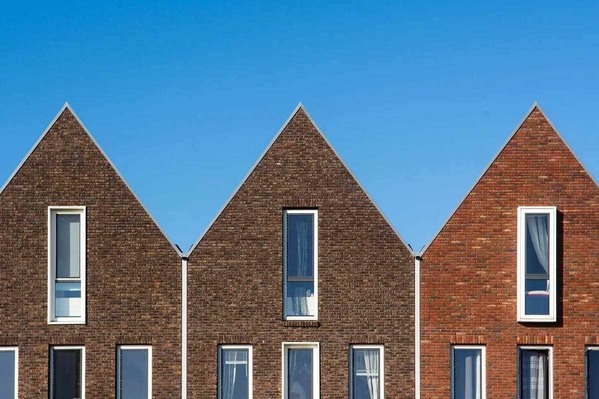 New brick homes with gabled roofs and tall windows against a blue sky